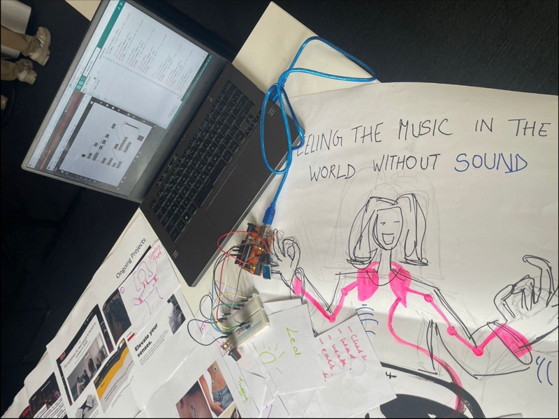 Laptop and Arduino on a large sheet drawn with a figure and the words feeling the music in the world without sound